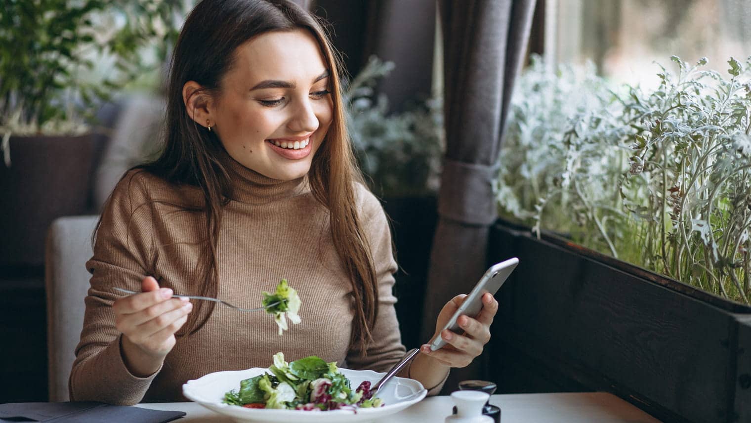 Woman eating salad looking at phone