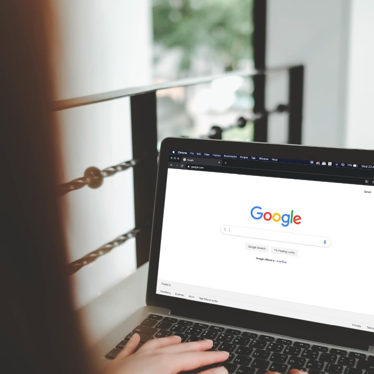 Hand on laptop showing Google home screen